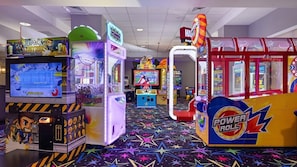 Eine Spielhalle mit verschiedenen Spielautomaten, darunter ein Jetpack Joyride-Automaten, ein Power Rollz-Automaten und ein Geschicklichkeitsarm-Automaten.