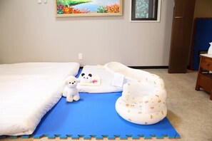 Ein Schlafzimmer mit einem Bett, einer blauen Matte, einem weißen Kopfkissen mit Panda-Motiv, einem weißen Stofftier und einem weißen Kopfkissen mit Muster.