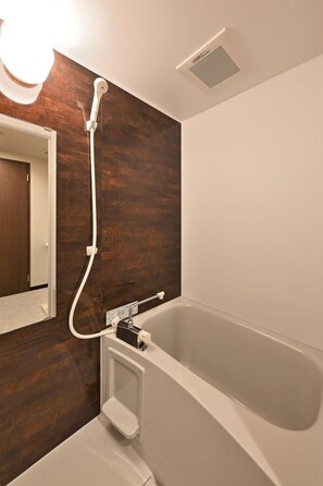 Ein modernes Badezimmer mit Badewanne, Dusche und Spiegel.