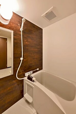 Ein modernes Badezimmer mit einer Badewanne, einer Duschbrause und einem Wandheizkörper.