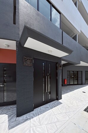 A modern building facade with a large entrance, a fire alarm box, and a visible window. - Just a short walk from Kokusai Street Enjoy Okin / Naha City Okinawa (Naha City)
