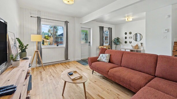 Un salon moderne avec un canapé, une table basse, un téléviseur et une lampe.