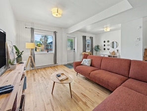 A modern living room with a sofa, a coffee table, a TV, and a lamp.