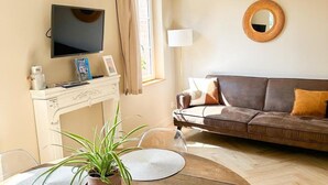 A living room with a TV, sofa, and dining table with placemats. - Roses, Veules les roses close to the beaches (Veules-les-Roses)