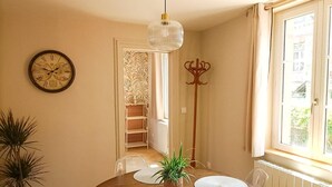 A dining area with a round table, a clock, a potted plant, and a window with a view. - Roses, Veules les roses close to the beaches (Veules-les-Roses)