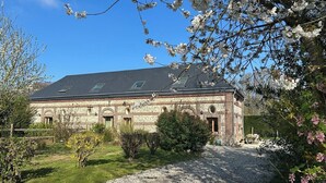 Een groot bakstenen gebouw met veel ramen, omringd door een grindpad en groen.
