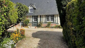 Ein traditionelles Fachwerkhäuschen mit Kiesauffahrt und gepflegtem Garten.