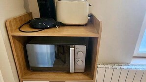 Eine Küchenzeile mit Mikrowelle, Toaster und Kaffeemaschine auf einem Holzboden.