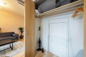 Ein gemütlicher Wohnraum mit einer Couch, einem kleinen Tisch, einem Blumentopf, einem Staubsauger und einer weißen Heizung.