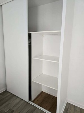 Un armario blanco con tres estantes y una puerta corredera.