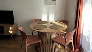 Uma sala de jantar com uma mesa redonda, seis cadeiras e uma televisão sobre um armário de madeira.
