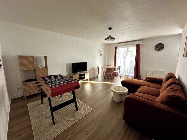A living room with a foosball table, a sofa, a TV, and a dining area with chairs and a table. - Escapade fécampoise - On the heights of Fécamp (Fécamp)