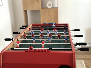 A foosball table with red and blue figures, set in a room with a wooden floor and a white wall. - Escapade fécampoise - On the heights of Fécamp (Fécamp)