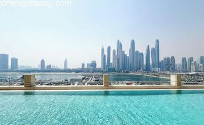 A waterfront view with a pool and a city skyline in the background. - Beachfront Living With Marina Skyline Views (Dubai)
