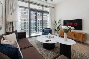 A modern living room with a sofa, coffee table, and a TV displaying 'NETFLIX'. - Beachfront Living With Marina Skyline Views (Dubai)