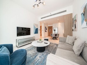 A modern living room with a TV, sofa, and coffee table. - Beachfront Living With Marina Skyline Views (Dubai)