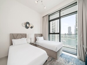 A modern hotel room with two beds, a large window with a city view, and a decorative wall piece. - Beachfront Living With Marina Skyline Views (Dubai)