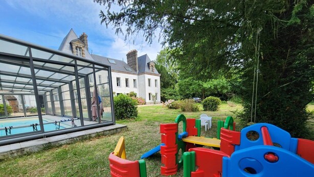 Una piscina vetrata adiacente a un'area giochi in un giardino.