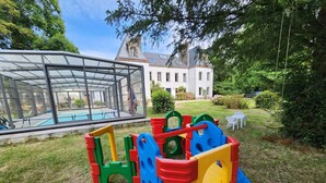 Un’area giochi con strutture colorate e, sullo sfondo, una piscina coperta in vetro.