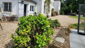 Una casa a due piani con un ampio giardino, una zona relax esterna e cielo sereno.