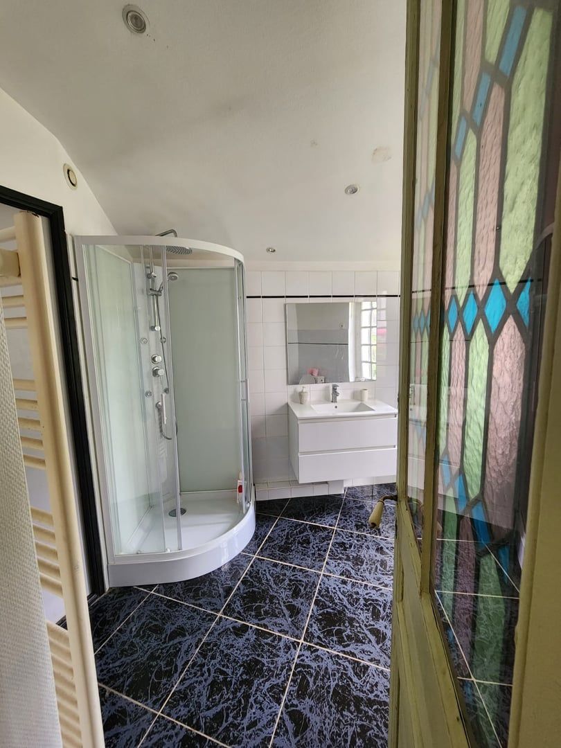 A modern bathroom with a glass-enclosed shower, white vanity, and a tiled floor.
