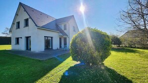 Une maison à deux étages, dotée d’un toit en pente, d’un porche à l’avant et d’une pelouse bien entretenue.