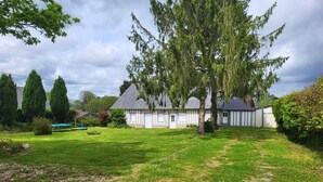 A white building with a grey roof, surrounded by a well-maintained lawn and trees. - Old-fashioned charm with modern comforts (Doudeville)