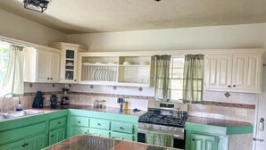 Una cucina con mobili verdi, un piano di lavoro in granito, un fornello e un lavello.