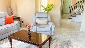Un soggiorno con un divano grigio, una poltrona coordinata, un tavolino in legno e un tappeto decorato.