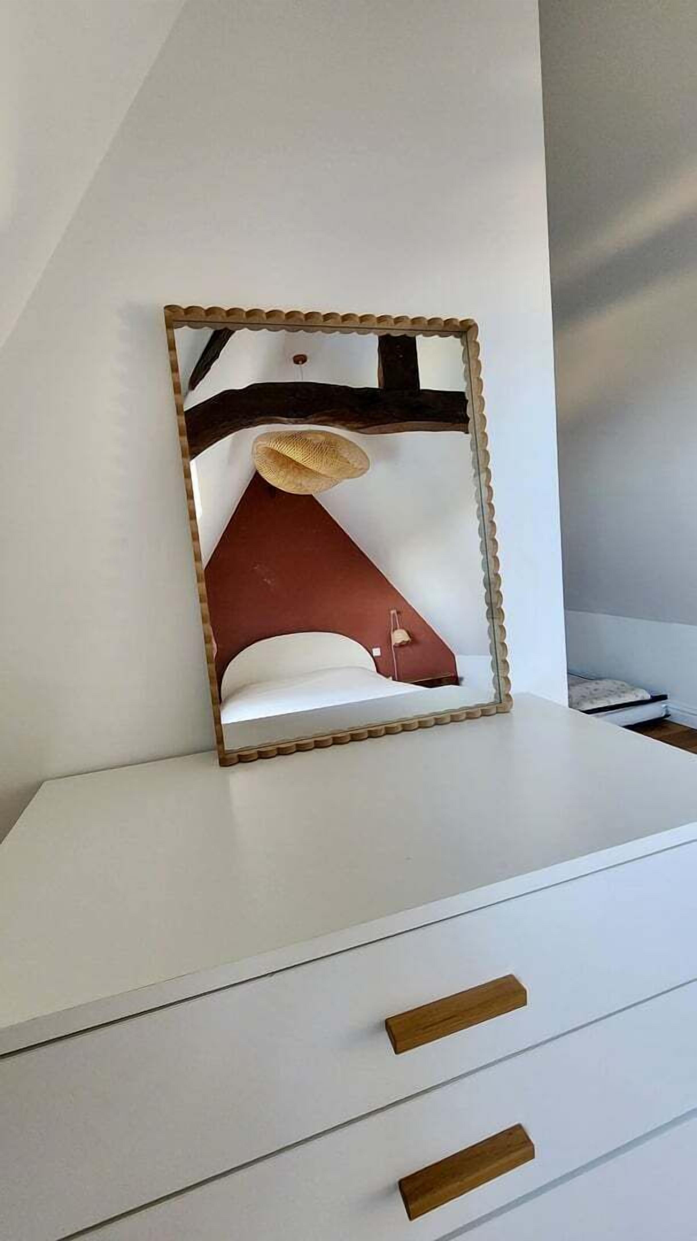 A white dresser with two drawers and a mirror with a wooden frame.