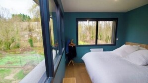 Ein Schlafzimmer mit einem großen Bett, einem Fenster und Blick ins Freie.
