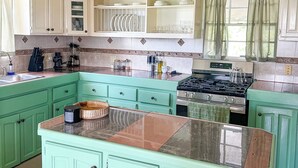 Una cocina con armarios verdes, una isla central y una estufa.