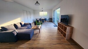 A modern living room with a sofa, coffee table, and TV stand. - The countryside at the edge of the sea (Manneville-ès-Plains)