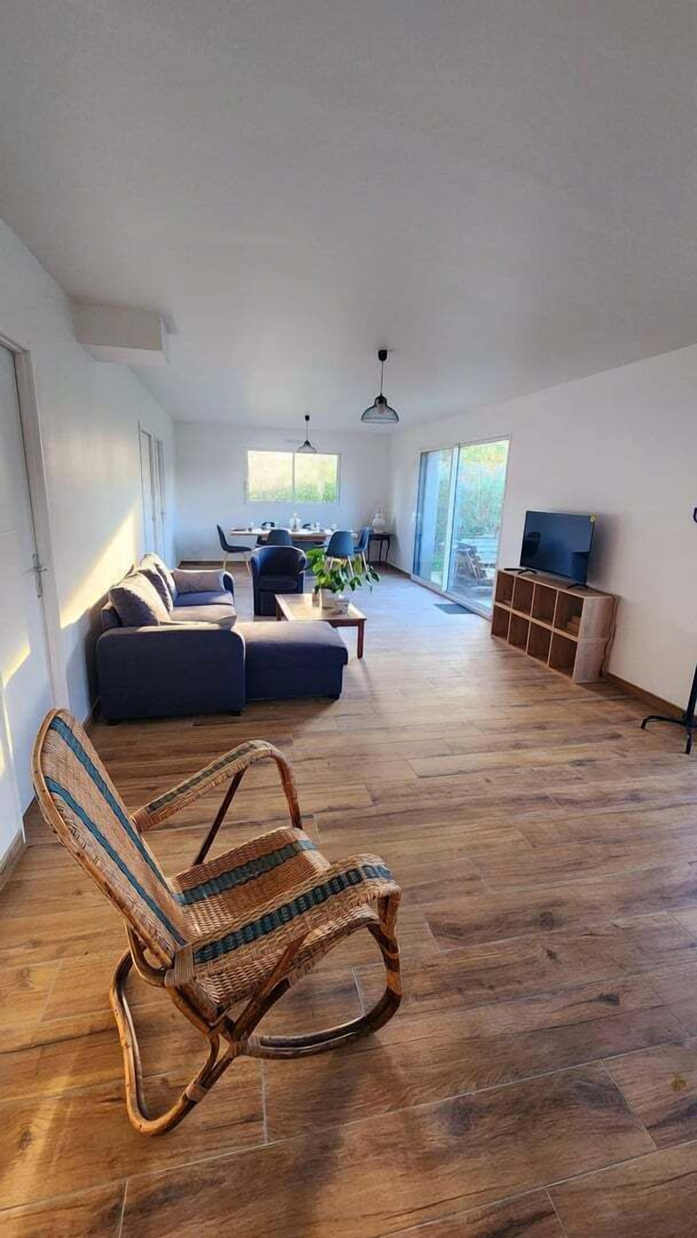 Ett rymligt vardagsrum med ett stort fönster, en soffa, ett matbord och en tv.