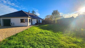 A single-story house with a garage, a covered porch, and a well-maintained lawn. - The countryside at the edge of the sea (Manneville-ès-Plains)