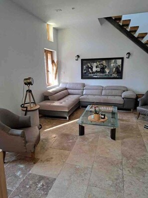Una sala de estar con un sofá modular, una mesa de centro de vidrio y un cuadro en la pared.