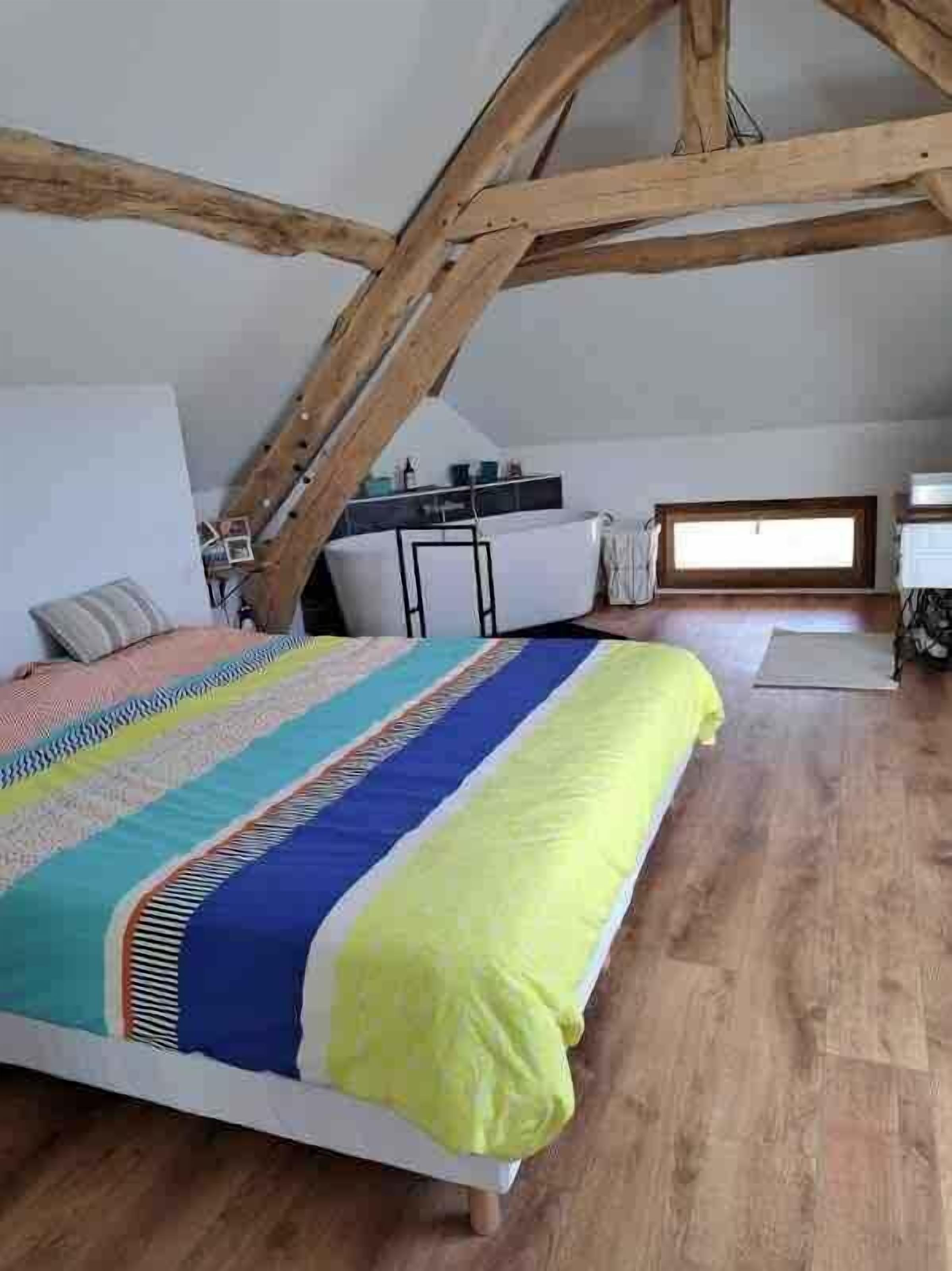 Un dormitorio con cama, escritorio y ventana.