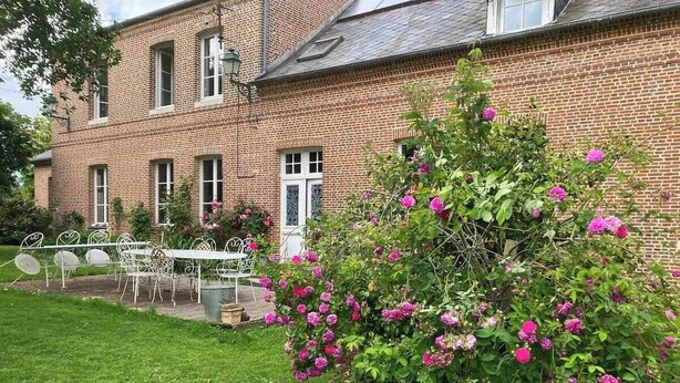 A brick building with a garden and outdoor seating area.