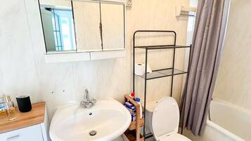 A bathroom with a sink, toilet, and a metal shelf unit.