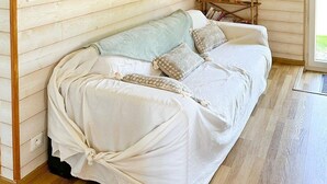 Ein gemütlicher Raum mit Holzwänden, einer gepolsterten Couch, einem kleinen Holztisch und einem hängenden Schild.