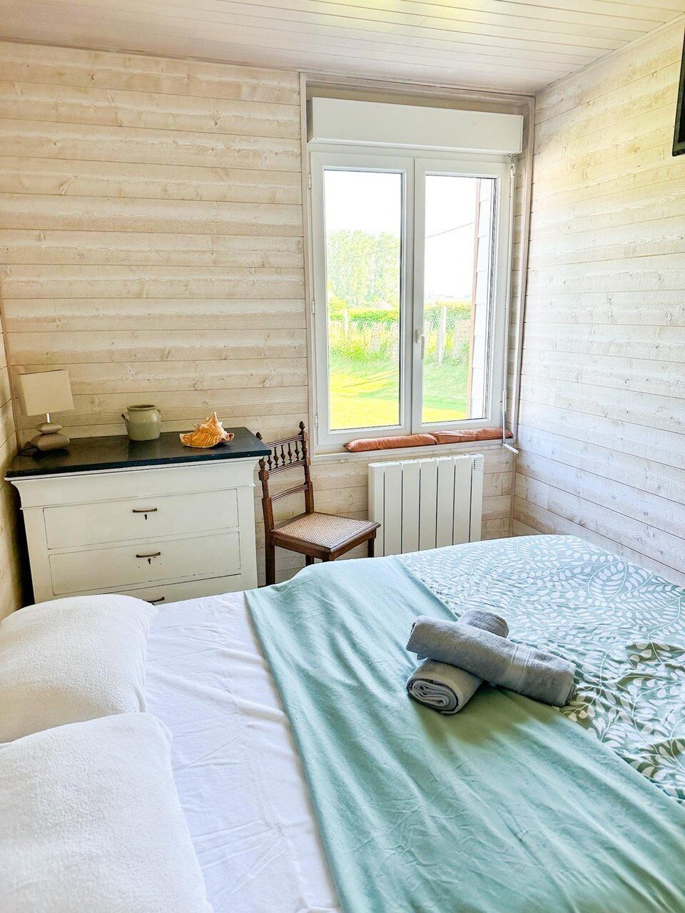 Makuuhuone, jossa on sänky, tuoli, työpöytä, ikkuna ja patteri.