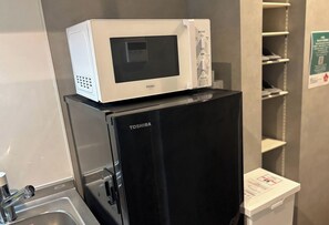 Un réfrigérateur Toshiba sur lequel est posé un four à micro-ondes de la marque Haier.