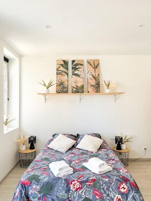 Ein Schlafzimmer mit einem Bett, zwei Nachttischen, einem Fenster und einem Wandregal mit Dekoration.