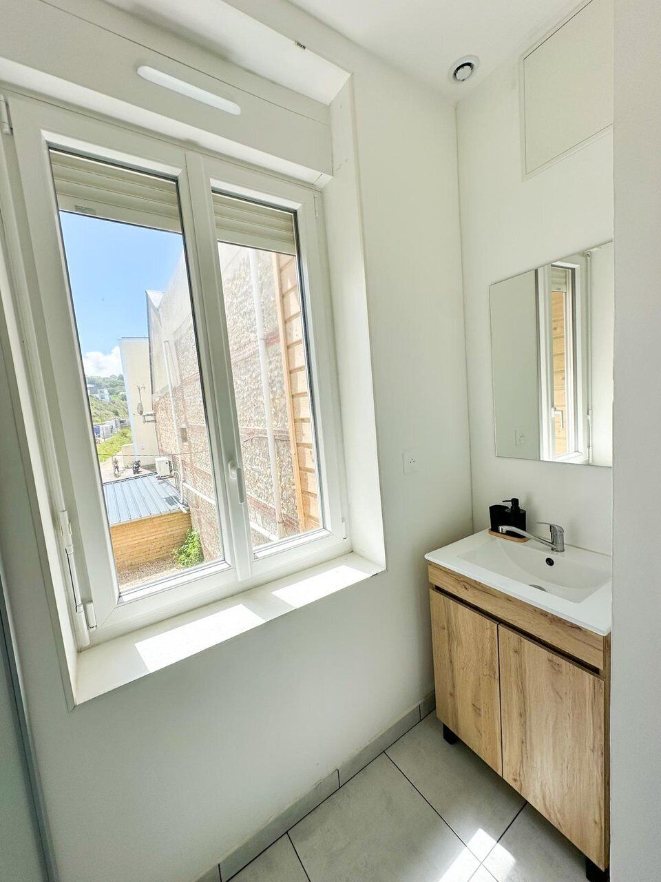 Ein Badezimmer mit Fenster, Waschbecken und Spiegel.