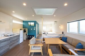 Une chambre moderne et compacte, dotée d’une kitchenette, d’un canapé, d’une table et d’un lit.