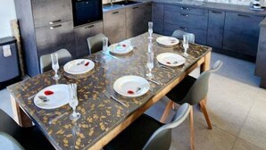 A modern kitchen with dark cabinets, a dining table set for four, and a patterned backsplash. - Cozy cottage near the sea (Cany-Barville)