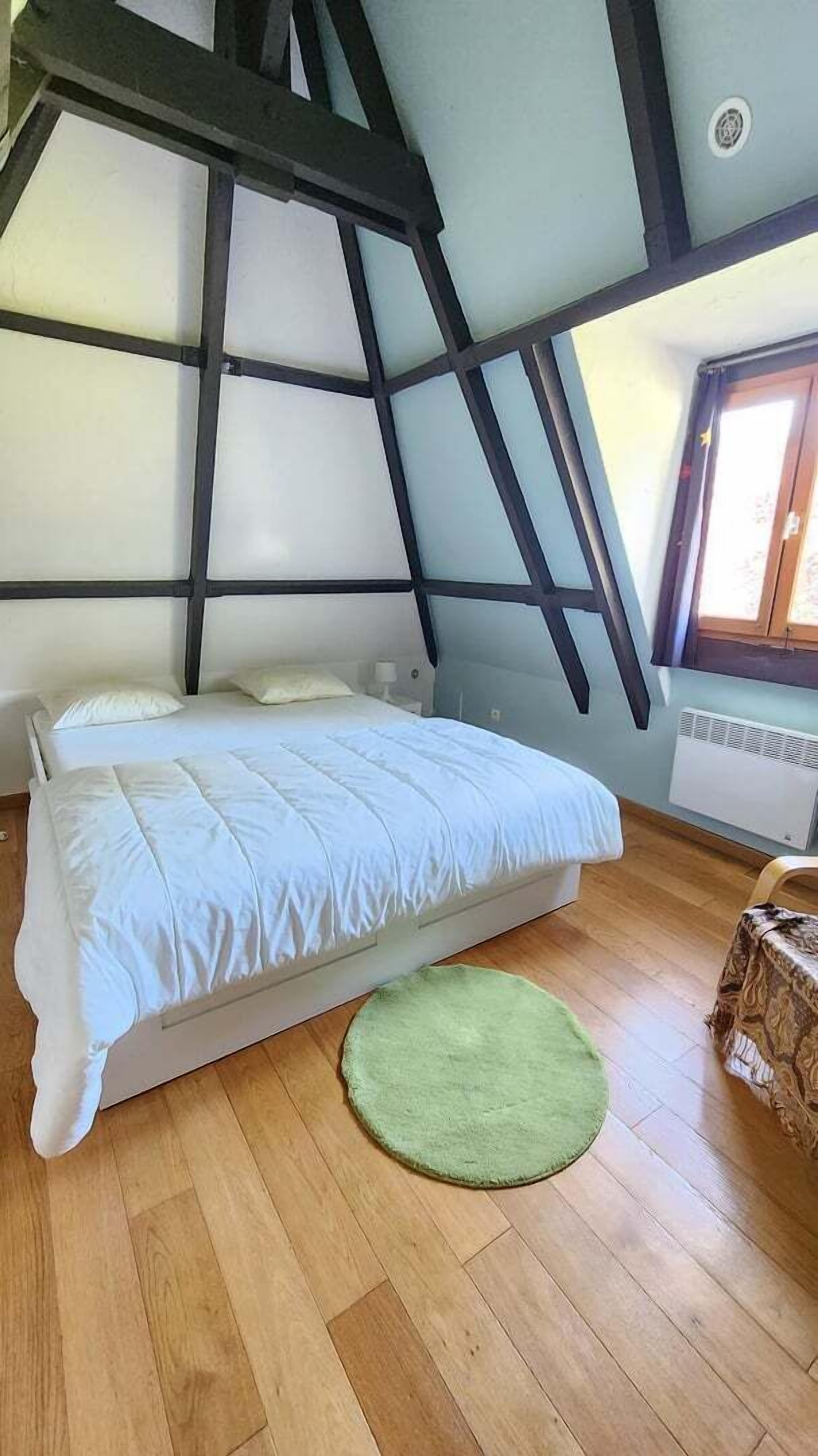 Ein Schlafzimmer mit einem Bett, einem grünen Teppich, Holzboden und einem Fenster mit Blick.