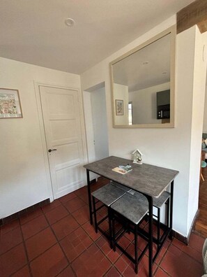 A small dining area with a table and bench, a white door, and a large mirror on the wall.