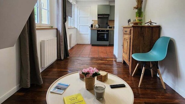 A modern apartment with a kitchen, dining area, and a small round table with a book and a glass. - Idyllic Normandy stay (Veules-les-Roses)