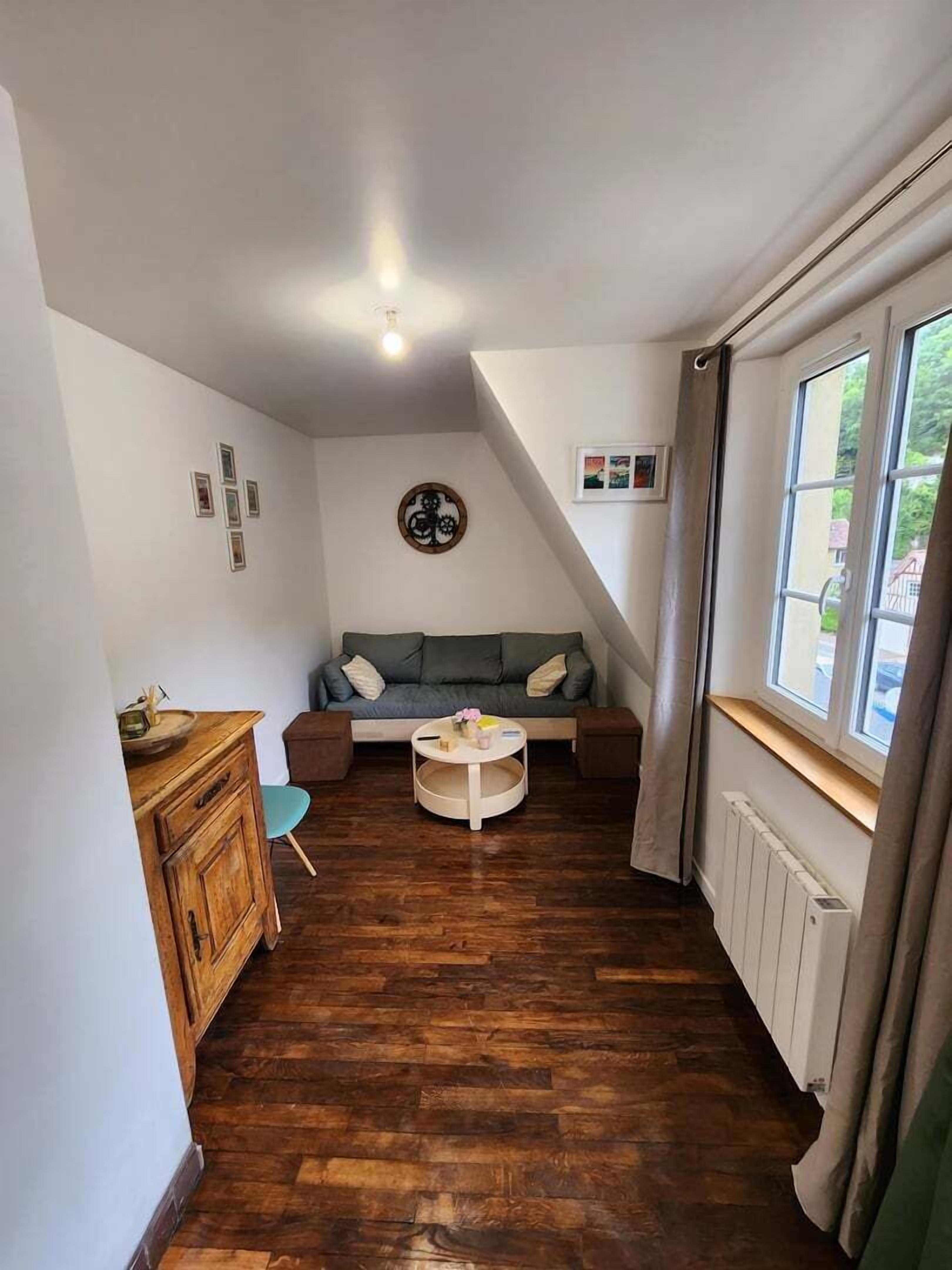 A cozy room with a wooden floor, a sofa, a small round table, and a cabinet.